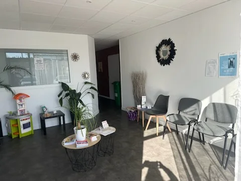 La salle d'attente du cabinet, claire, avec des plantes et quelques chaises